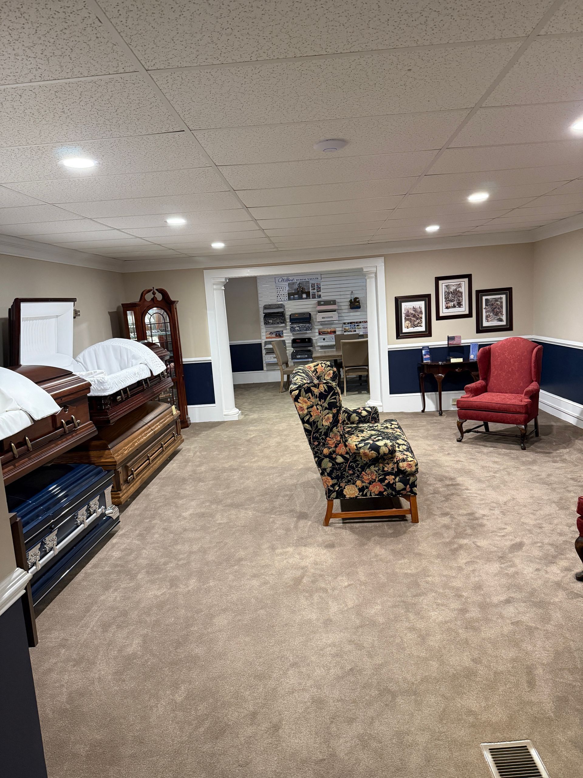 Carpeted room with quilt racks, a red armchair, and framed wall art in a cozy interior.