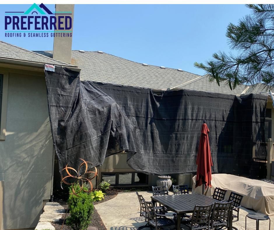 Backyard patio with black shade tarps, outdoor table set, and patio umbrella beside a house