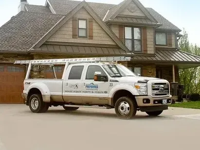 A white truck is parked in front of a large house.