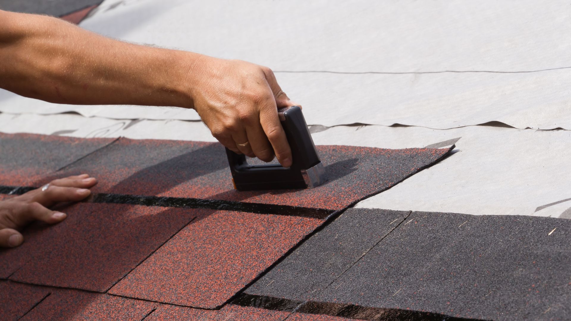 A person is laying shingles on a roof.