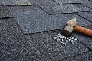 A hammer and nails are laying on top of a roof.