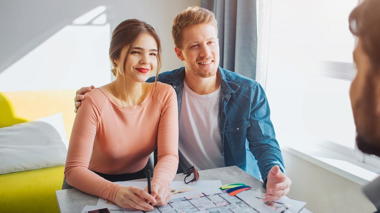 A man and a woman are sitting at a table looking at a blueprint.