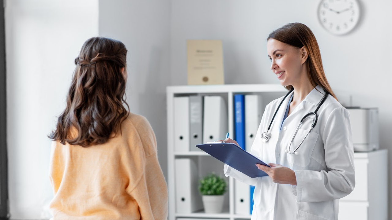A doctor is talking to a patient while holding a clipboard.