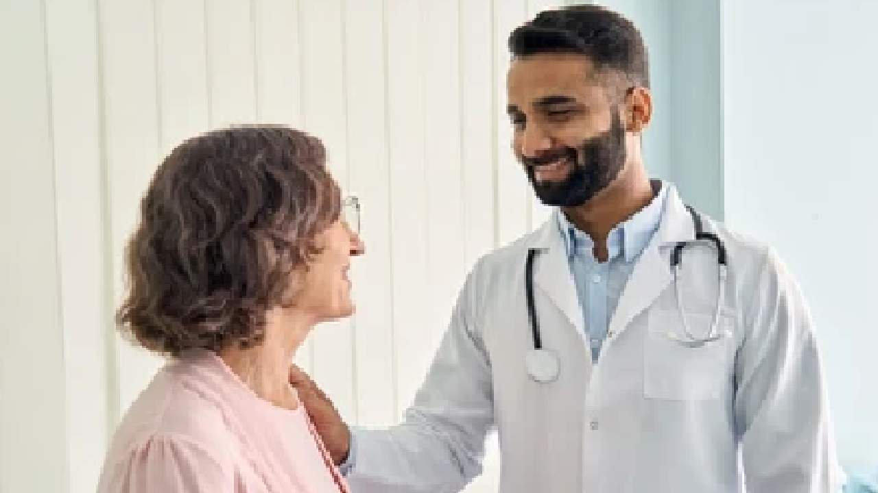 A doctor is talking to an elderly woman in a hospital room.