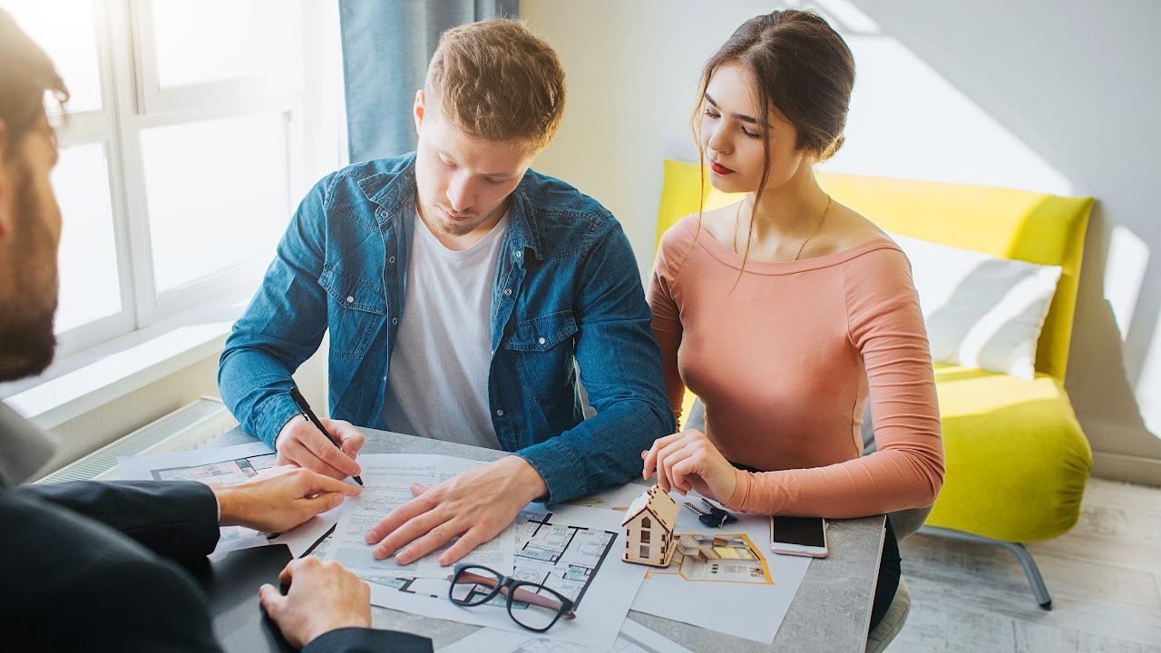 A man and a woman are sitting at a table looking at a blueprint.