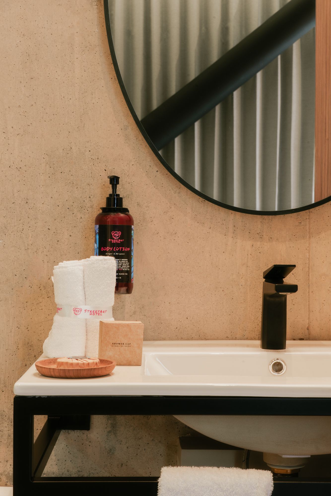 Bathroom sink with black faucet, towels, soap, and a round mirror.