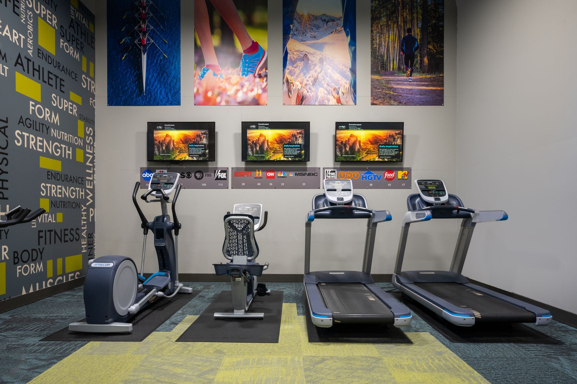 Gym interior with elliptical machine, stationary bike, treadmills, and TVs; colorful art on wall.