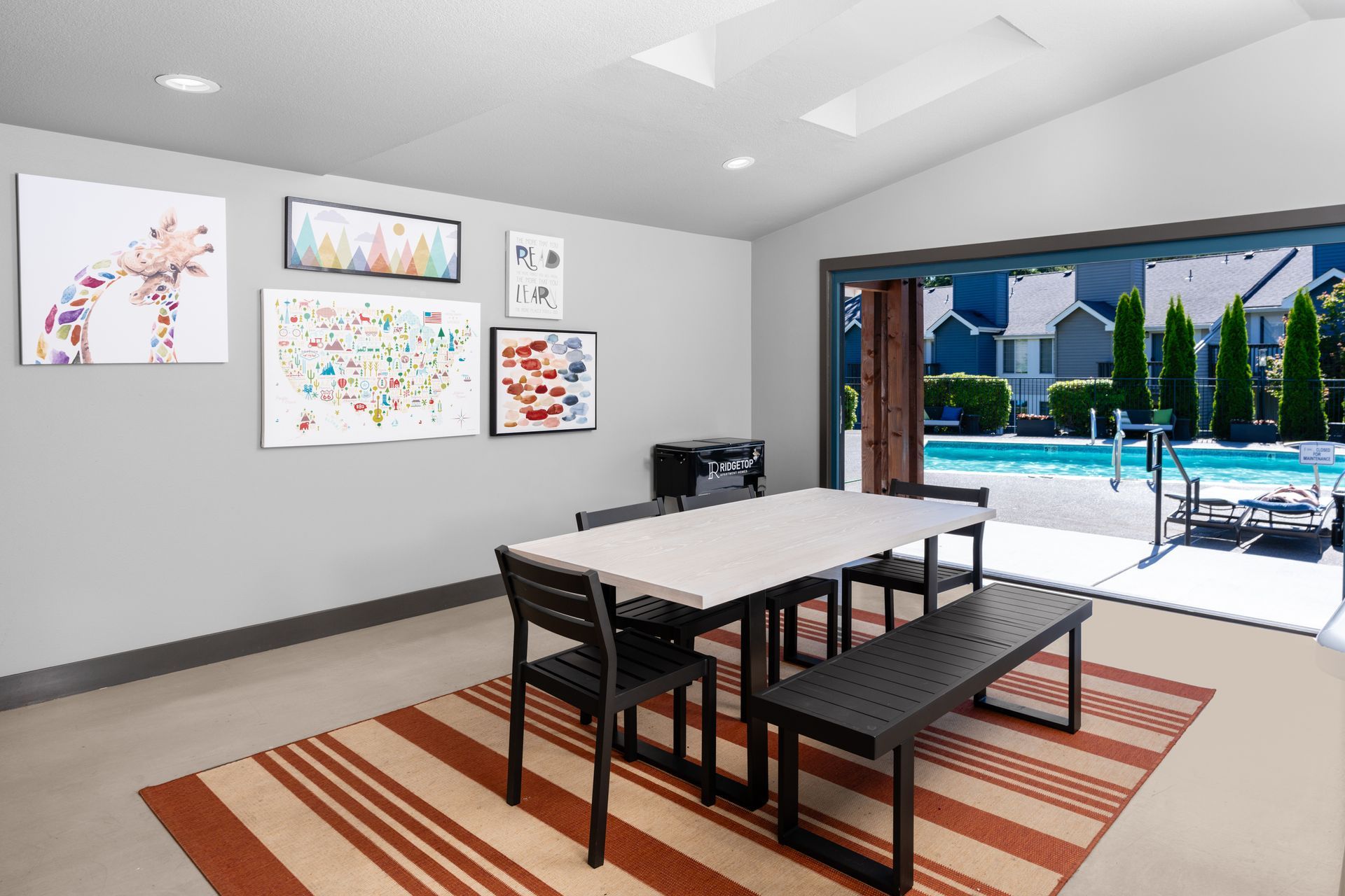 Room with table and chairs, decorated with art. View of pool through open sliding doors.
