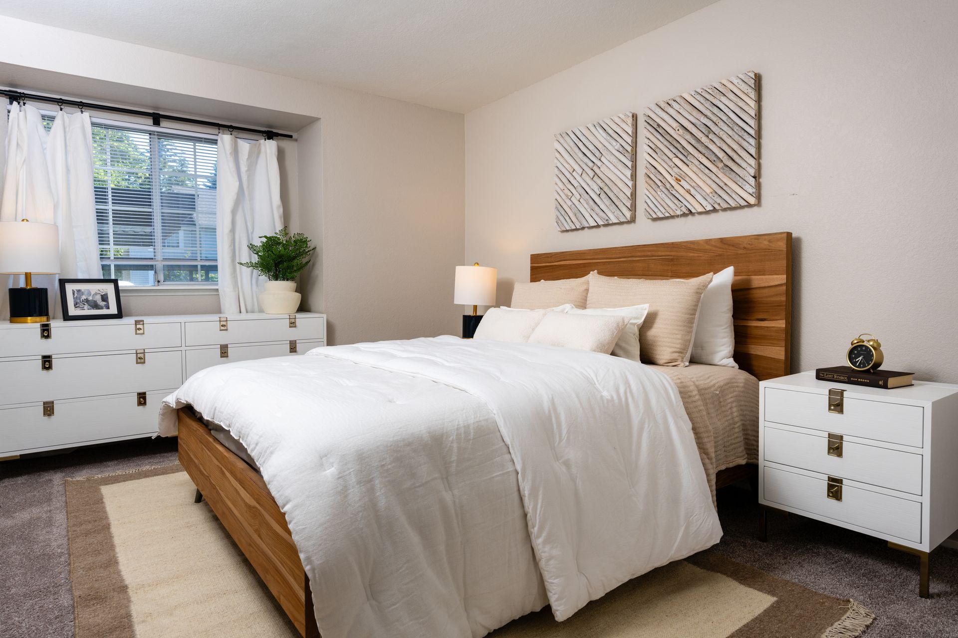 Bedroom with wooden bed, white bedding, nightstand, dresser, and wall art.