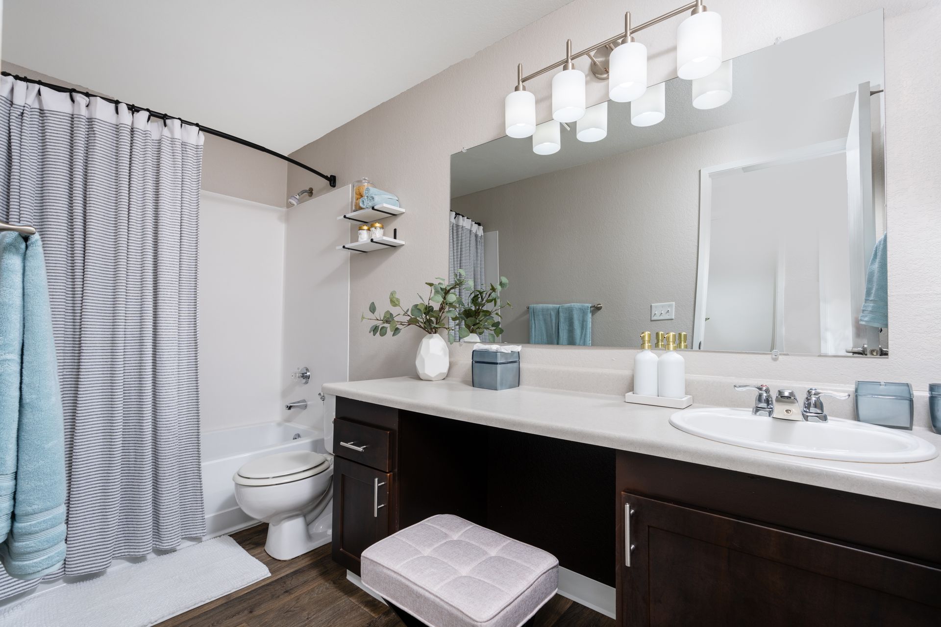 Bathroom with a vanity, toilet, and shower. Gray and white accents, dark brown cabinets, and a white countertop.