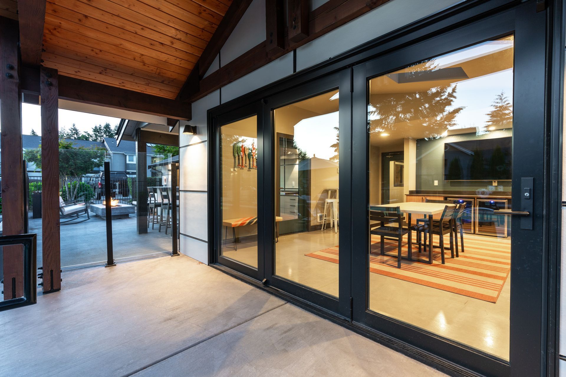 Patio with large glass doors leading to a dining area. Outside view includes a fire pit and seating.