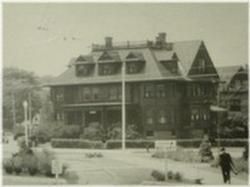 Historic house with dormer windows, front porch, and a flagpole in front