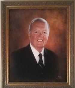 Framed portrait of a smiling man in a dark suit and tie on a warm brown background