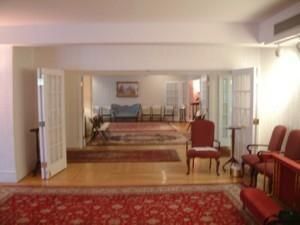 Living room with red upholstered chairs, patterned rugs, and a sofa in a softly lit interior