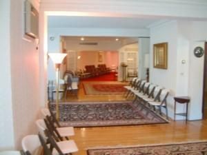 Interior room with mirrors, chairs along the wall, a floor lamp, and a red seating area in the background