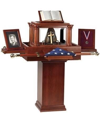 Wooden funeral casket on pedestal with folded U.S. flag, framed photo, and memorial items