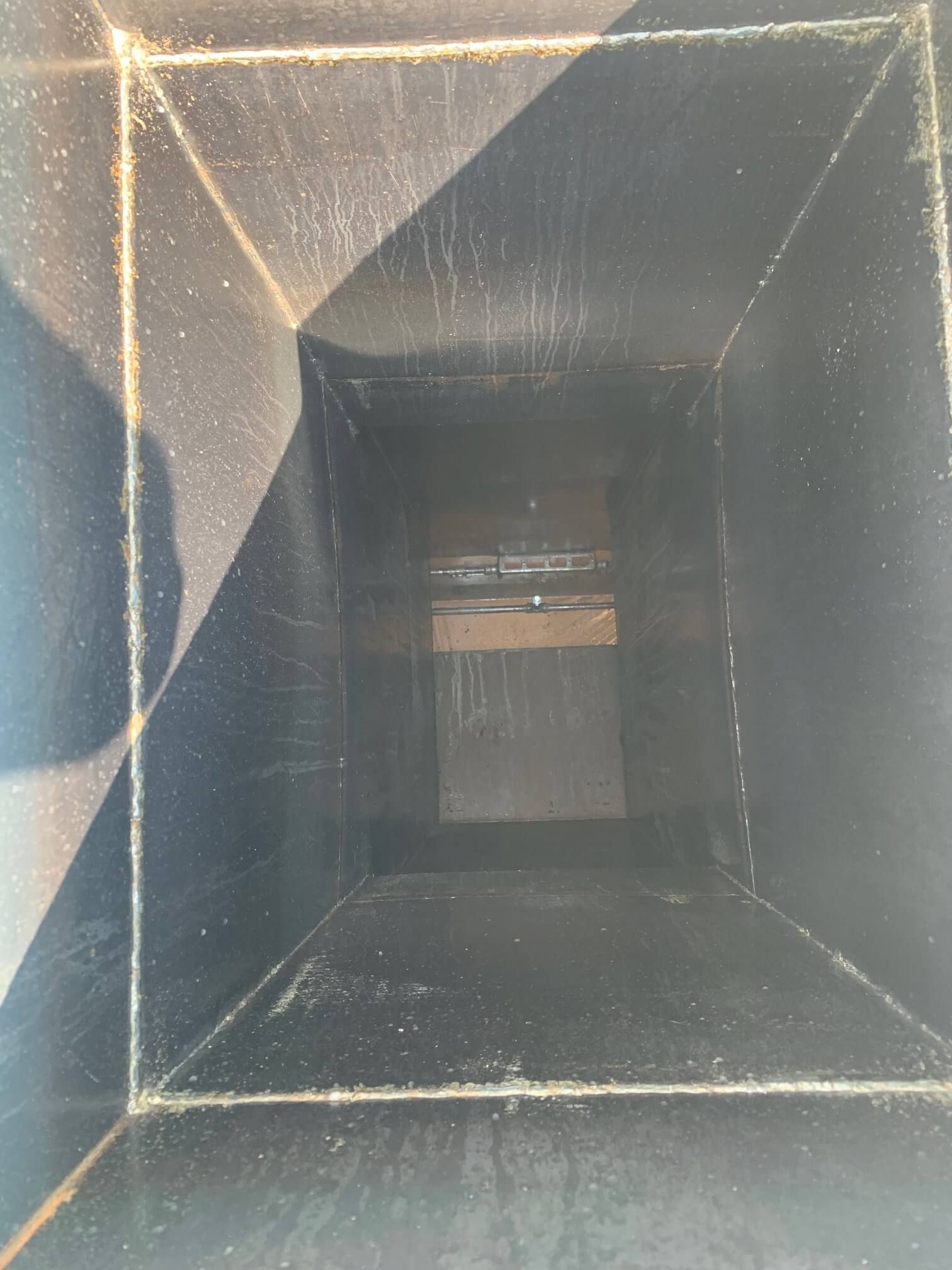 The inside of a vent with a shadow on the wall.