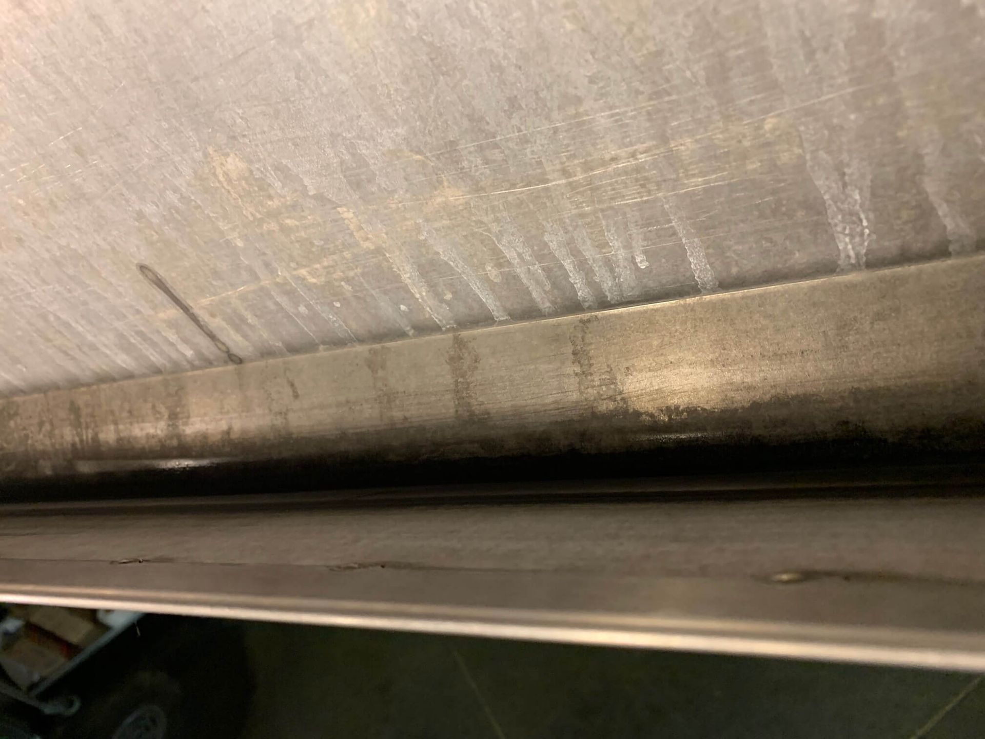 A close up of a stainless steel pipe on a wall.