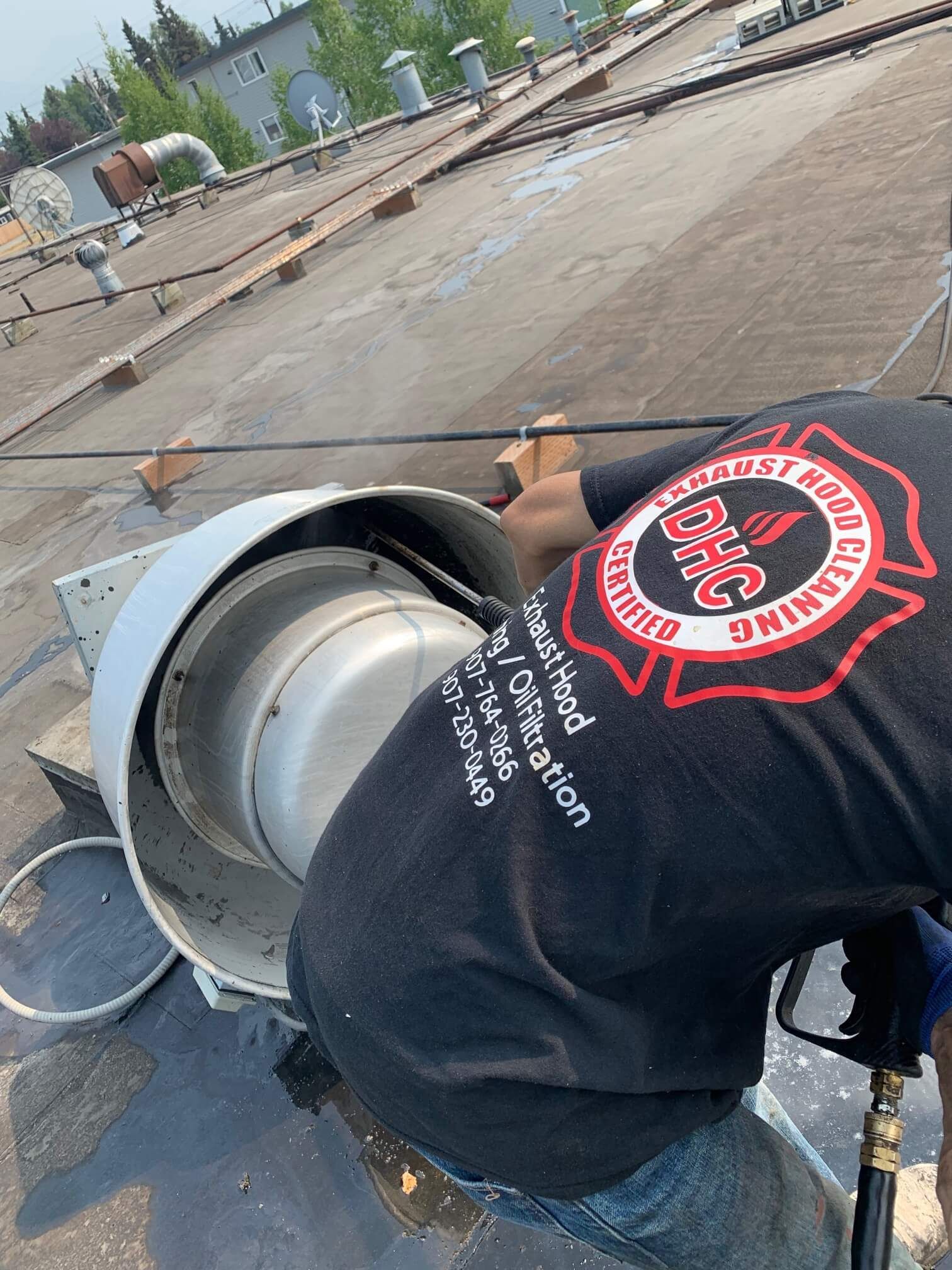 A man is working on a fan on a roof.