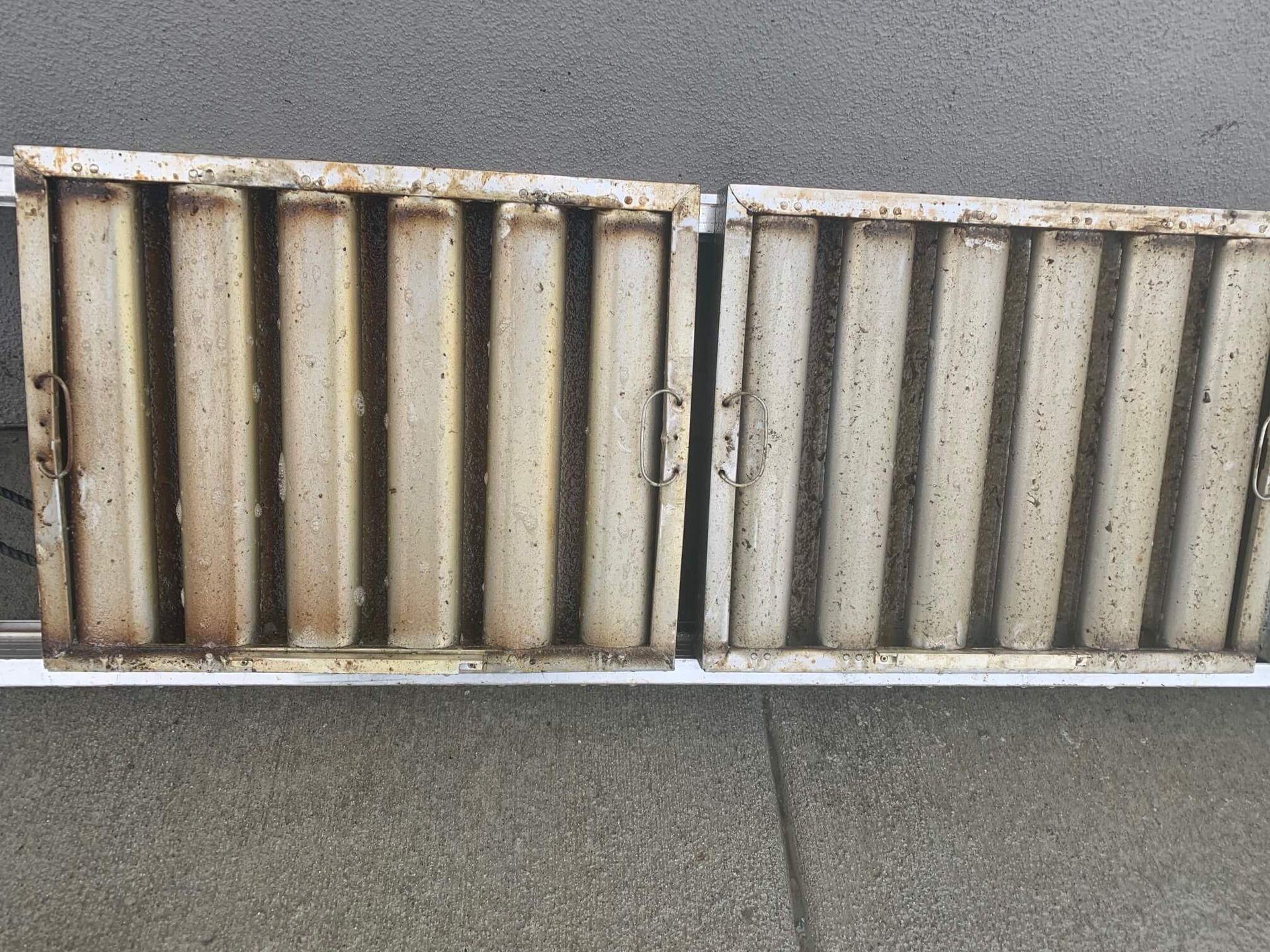 A pair of rusty metal pipes are sitting on a sidewalk.