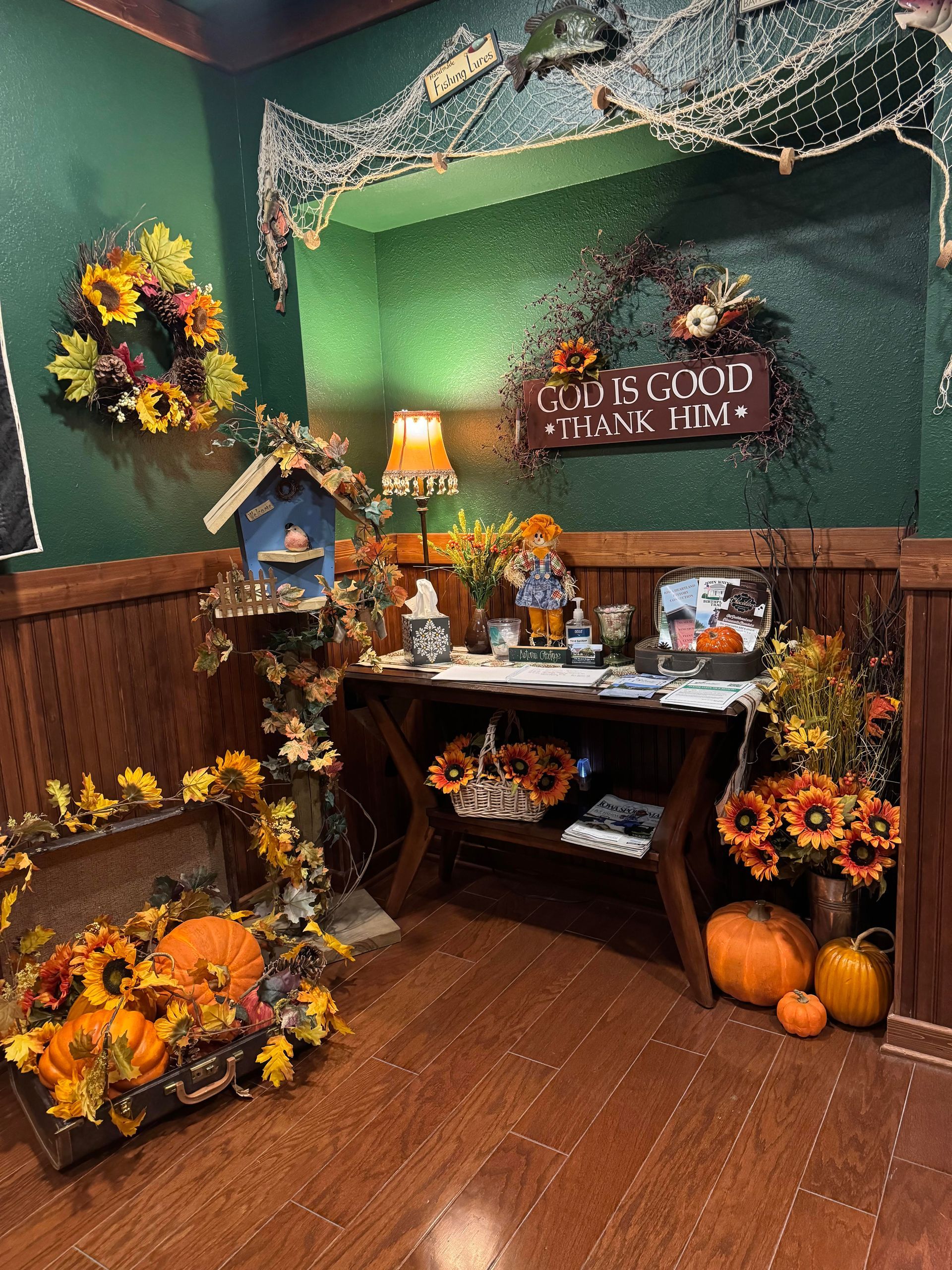 A wooden entryway with autumn decor: wreaths, pumpkins, a birdhouse, and a sign that reads