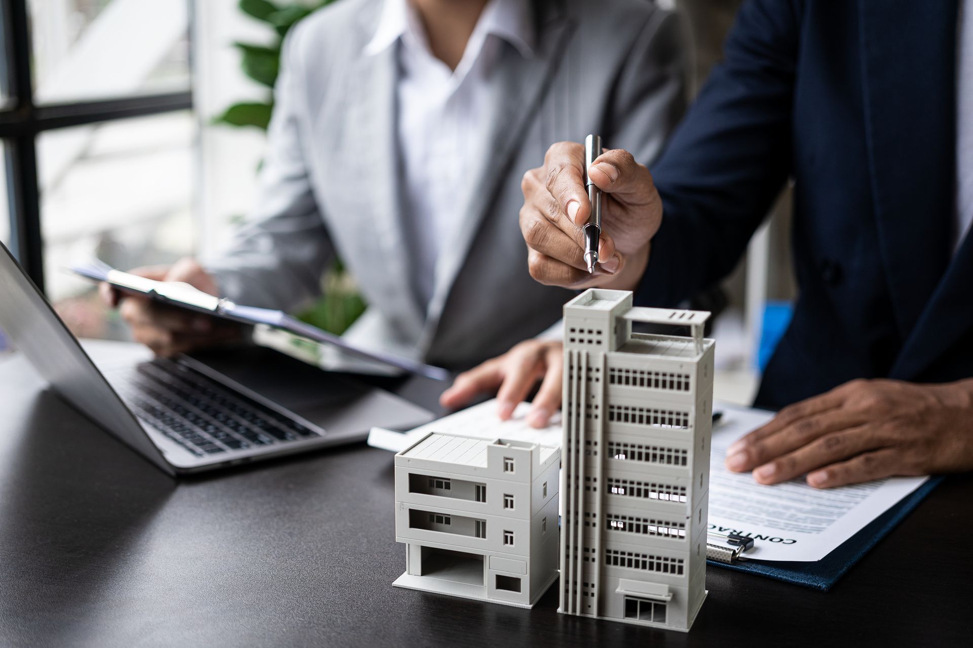 A man is holding a pen in front of a model of a building.