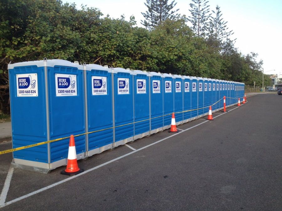 A Row of Blue Portable Toilets Are Lined Up in a Parking Lot — Hire A Loo in Caloundra, QLD