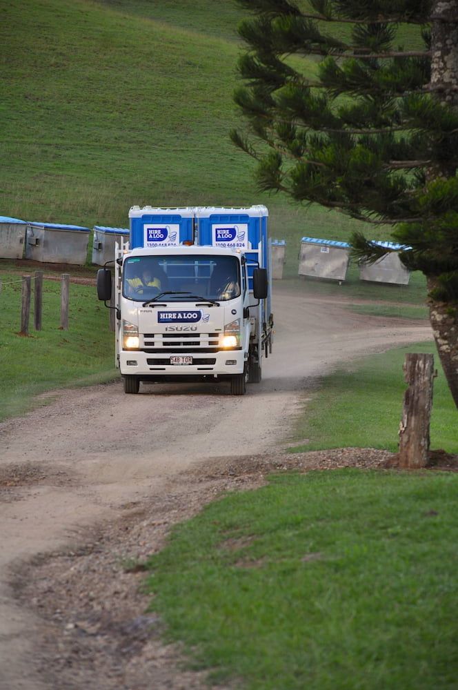 A White Truck is Driving Down a Dirt Road — Hire A Loo in Coolum Beach, QLD