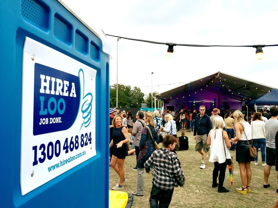 A Group of People Are Standing in Front of a Hire a Loo Sign — Hire A Loo in Coolum Beach, QLD