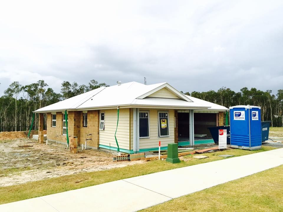 A House Under Construction With a Blue Portable Toilet in Front of It — Hire A Loo in Coolum Beach, QLD