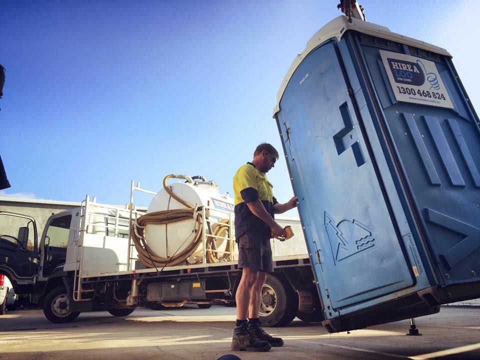 A Man is Loading a Portable Toilet Into a Truck — Hire A Loo in Gympie, QLD