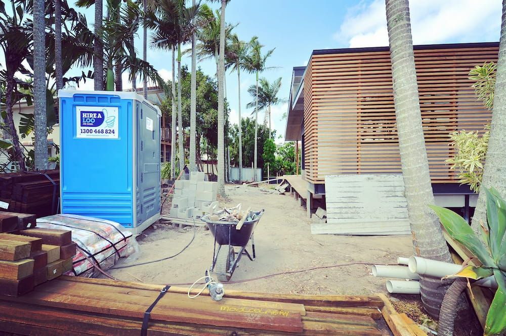 A Blue Portable Toilet Next to a Building Under Construction — Hire A Loo in Gympie, QLD