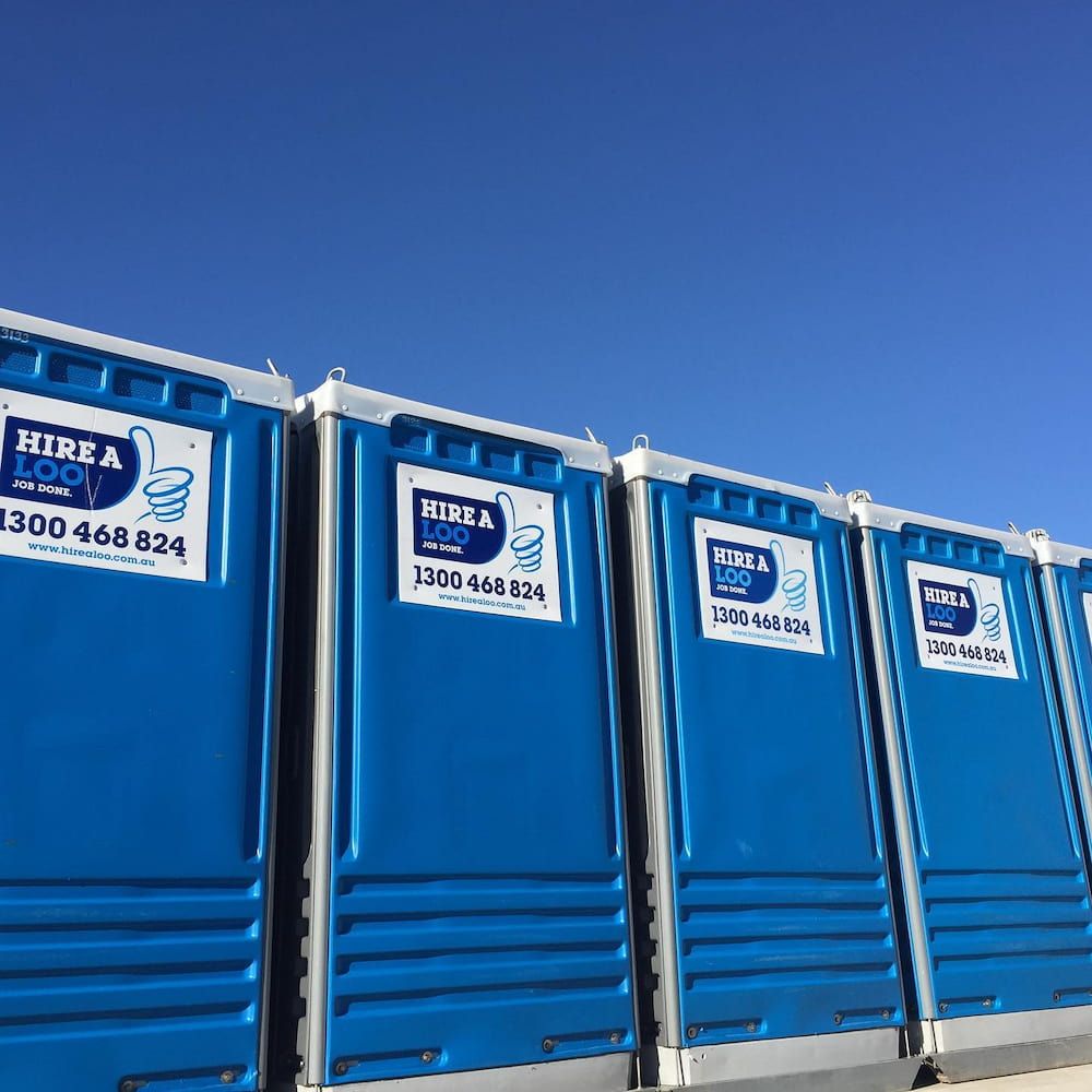 A Row of Blue Portable Toilets Are Lined Up in a Row — Hire A Loo in Mooloolaba, QLD