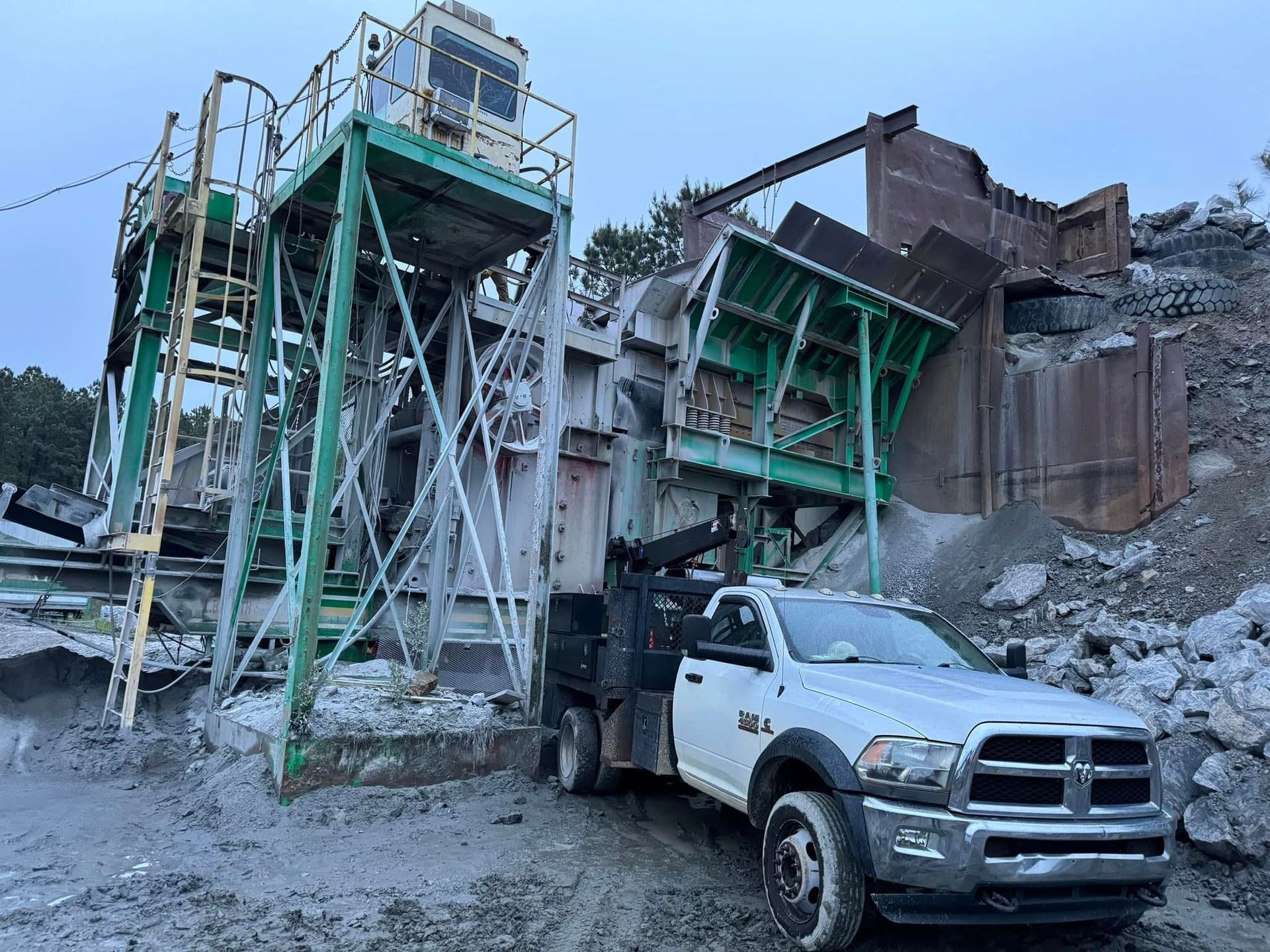 A white pickup truck parked near a large industrial rock crushing machine. Commercial mobile welding
