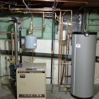 Heating system with copper pipes, beige furnace, and gray water heater in a basement.