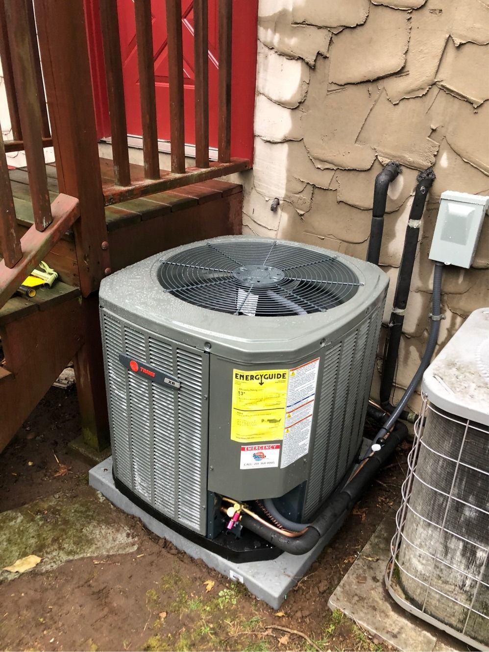 Trane air conditioning unit sitting on concrete slab next to a building.