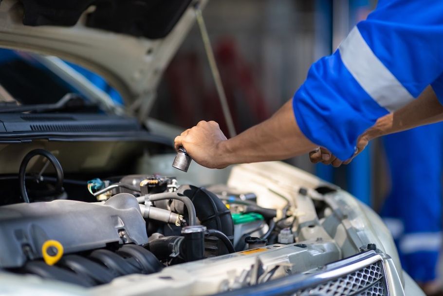 Mechanic inspecting engine bay of a car with the hood open