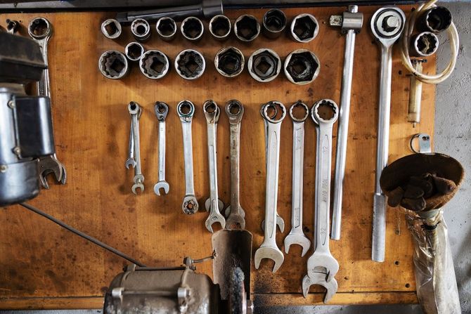 Workshop pegboard with neatly arranged wrenches, sockets, and tools on a wooden wall