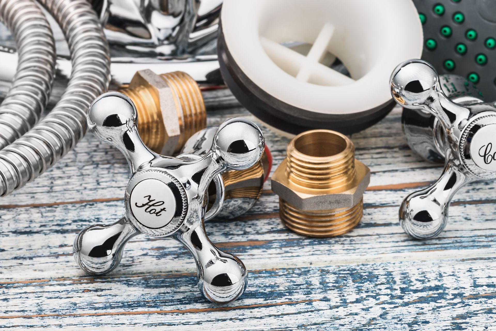 Chrome faucet handles, brass plumbing fittings, and a white drain on weathered wood.