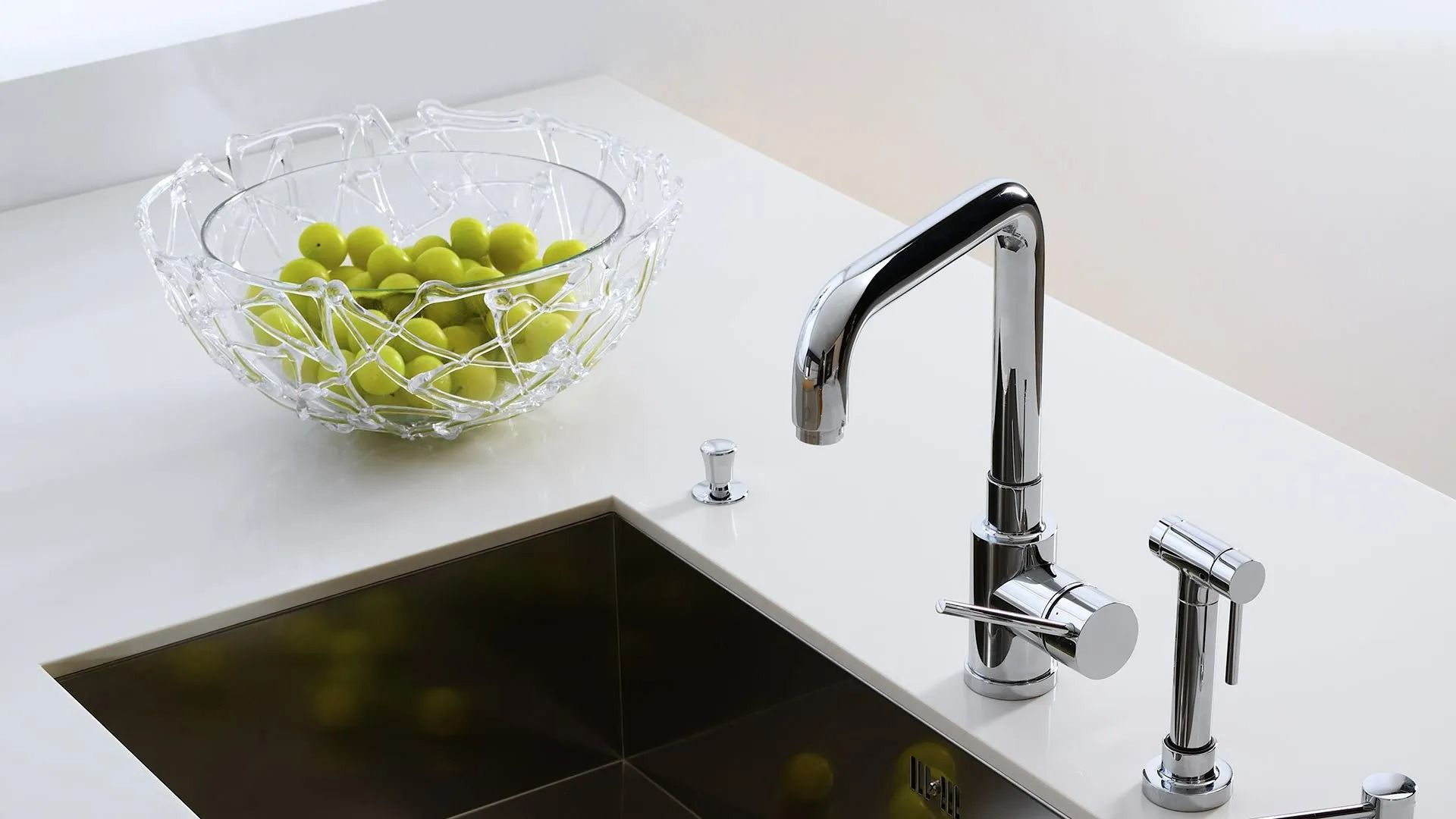 Stainless Steel Kitchen Sink With Chrome Faucet Sprayer And Bowl Of Green Grapes — David Talbot Plumbing in Cranbrook, QLD