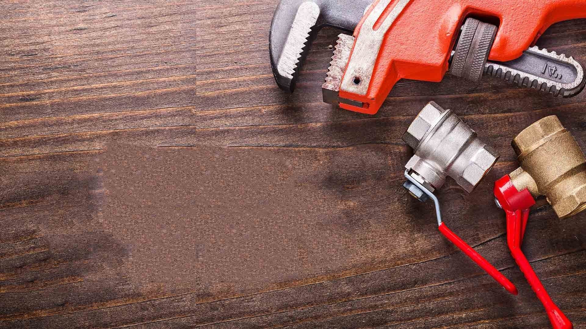 Plumbing Tools And Parts On Wooden Surface With Wrench Valve And Connectors — David Talbot Plumbing in Cranbrook, QLD