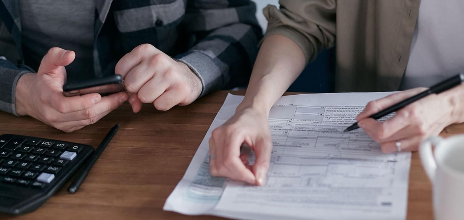 Couple reviewing financial paperwork with a calculator and phone at a table