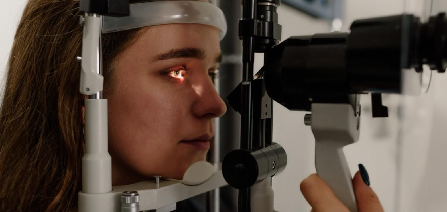 Woman having a comprehensive eye exam with an ophthalmic slit lamp device