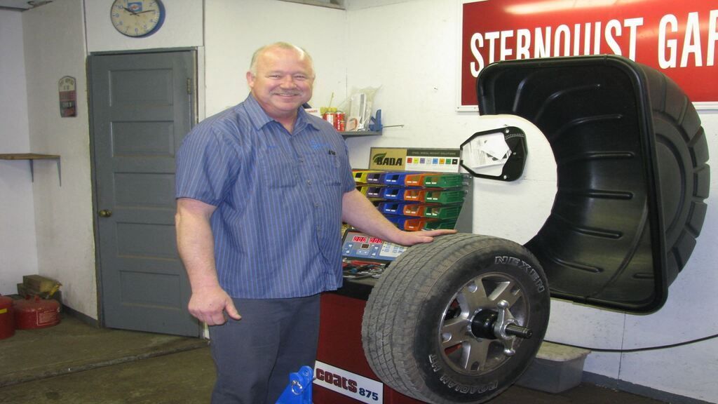 A man stands in front of a sign that says sternquist garage