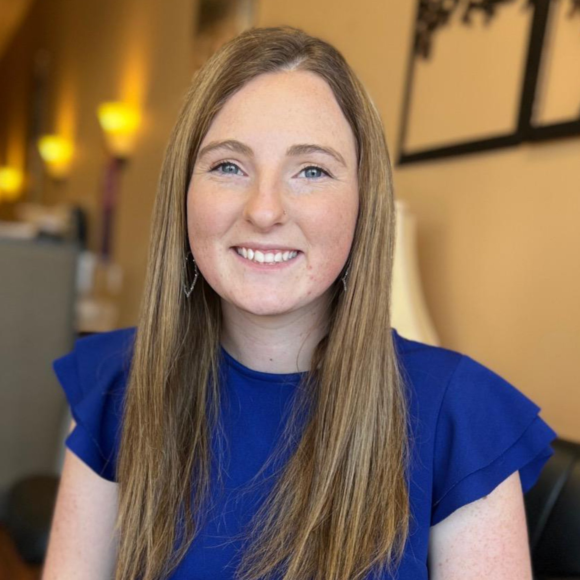 A woman in a blue shirt is smiling for the camera.