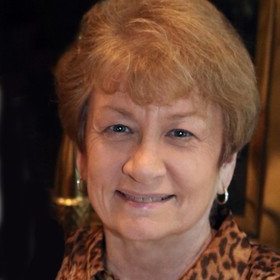 A close up of a woman 's face wearing a leopard print shirt and earrings.