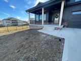 New house front porch with concrete walkway and unfinished dirt yard under a blue sky