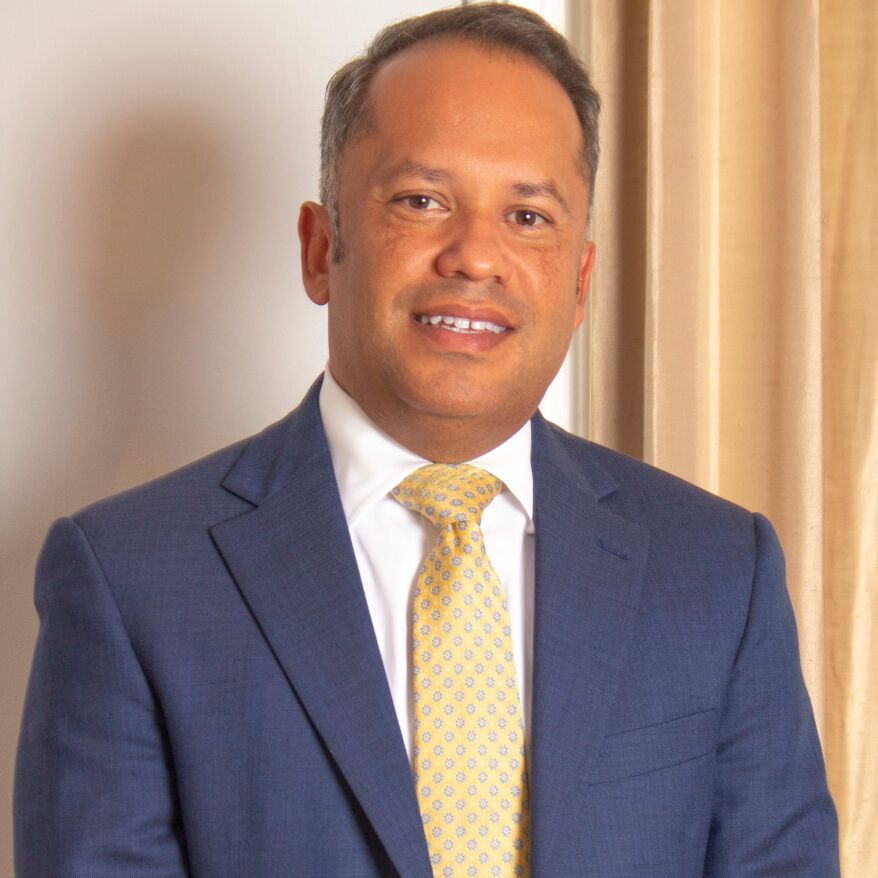 Portrait of a man in a blue suit and yellow tie against a light background