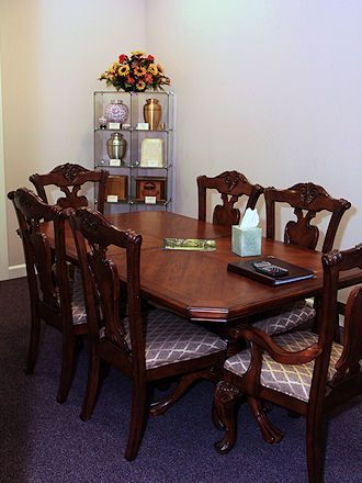 Dining room with dark wood table and chairs, a shelf with decor, and a floral centerpiece
