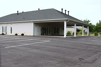 Empty parking lot beside a white building with a covered drive-through entrance